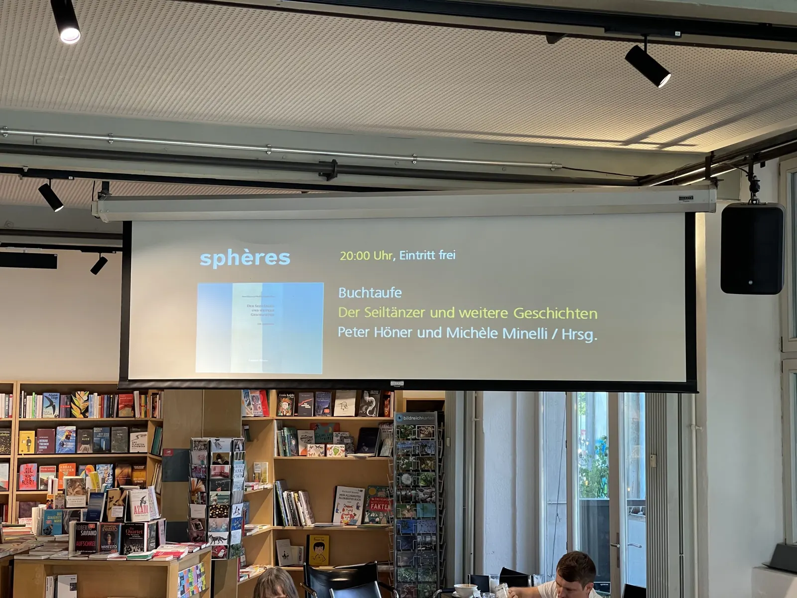 Die Leinwand im sphères kündigt die Buchtaufe an